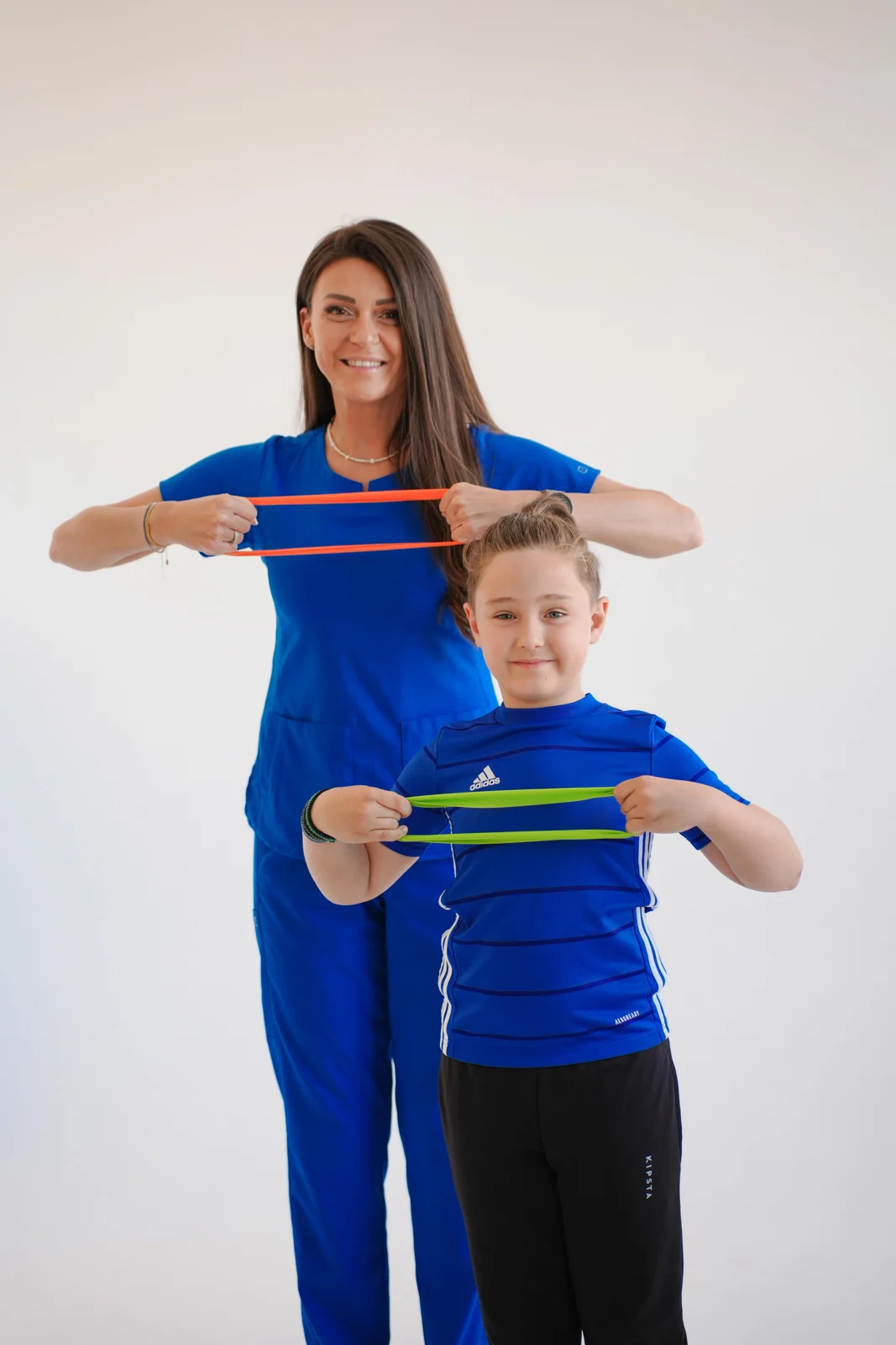 Mihaela și un copil, într-un exercițiu cu bandă elastică